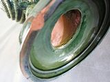 a green vase with a brown lid on a white table