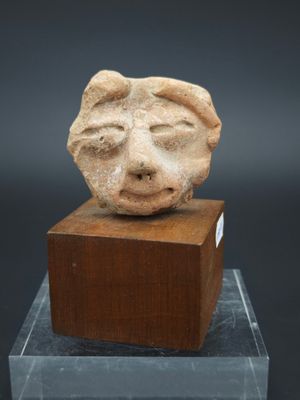 un gros plan d'une sculpture représentant un visage sur un bloc de bois