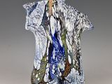 un vase bleu et blanc surmonté d'un oiseau