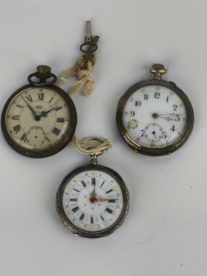three antique pocket watches are displayed on a white surface