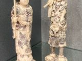 deux figurines représentant des personnes d'origine asiatique exposées dans une vitrine