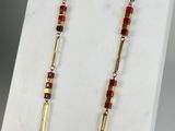 a close up of a necklace with red beads on a white surface