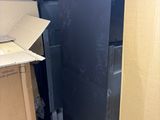 a black refrigerator in the middle of a room with boxes on the floor