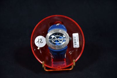 une montre rouge et bleue posée dans un récipient en verre