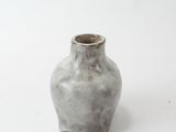 a small gray vase sitting on a white surface