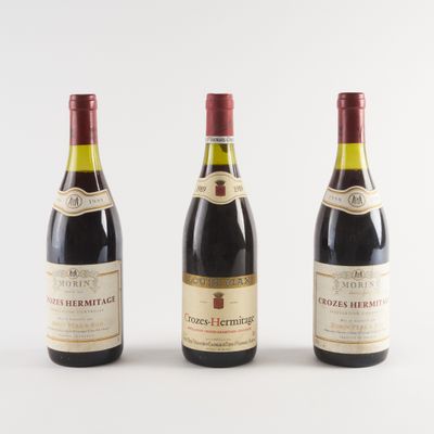 trois bouteilles de vin sont alignées sur une surface blanche