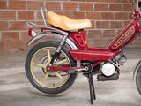 a small red motorcycle parked in front of a brick wall