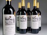 quatre bouteilles de vin rouge sont alignées sur une table