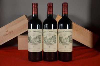 three bottles of red wine sitting next to a wooden box on a table