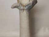 a white vase with a flower in it sitting on a table