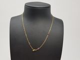 un collier à chaîne en or orné de pierres roses sur un mannequin