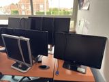 four computer monitors on a desk in an office