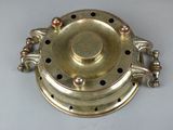a small brass object on a table with a white background