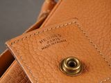 the inside of a tan leather purse with a metal button