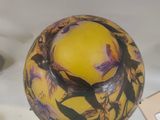 a yellow vase with a bird on it sitting on a table