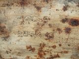 rust on a piece of wood that has some writing on it