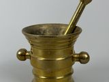 un mortier et un pilon anciens en laiton sur fond blanc