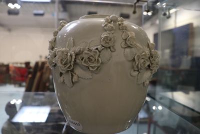 un vase blanc orné de fleurs, exposé dans une vitrine