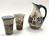 three cups and a pitcher sitting next to each other on a table
