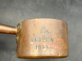 a small brass pot with a handle on a table