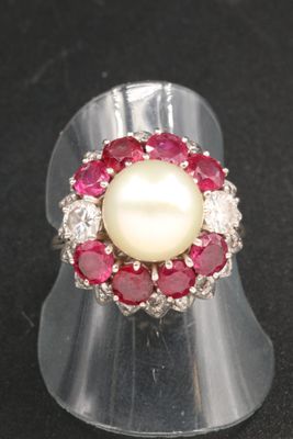 un gros plan d'une bague ornée d'une perle et de pierres rouges