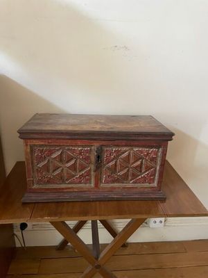 an old wooden chest sitting on top of a table next to a lamp