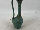 a green vase that is sitting on a white surface