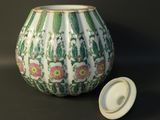 a white and green vase with a lid on a table