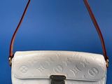 a hand holding a white louis vu vu bag