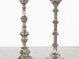pair of silver candlesticks on a table with a white wall in the background