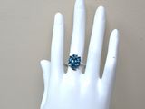 une bague sur la main d'un mannequin, sertie d'une topaze bleue