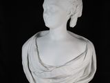 white marble bust of a woman wearing a tiable and a crown