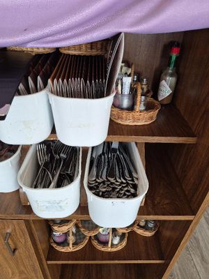 une étagère en bois sur laquelle sont posés des paniers contenant des couverts et des cuillères