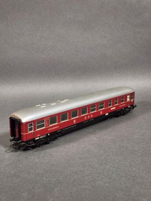 un wagon rouge et argenté posé sur une surface grise