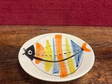 une petite assiette posée sur une table, sur laquelle se trouve un poisson