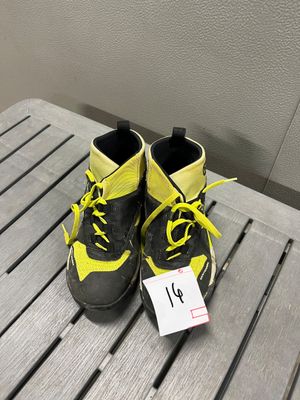 une paire de baskets noires et jaunes, avec des lacets jaunes, posée sur une table en bois