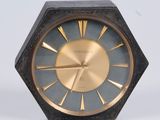 une horloge noire et or posée sur une surface blanche