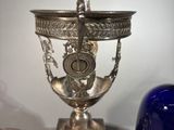 a silver vase and a blue bell on a table