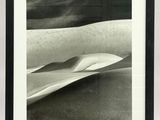 black and white photograph of a surfboard on a sandy beach