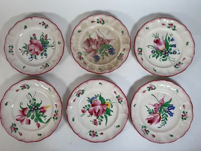 six plates with floral designs on them sitting on a white surface