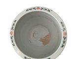 a white bowl with orange flowers on it on a white surface