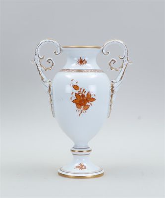 a white vase with orange flowers on it on a table