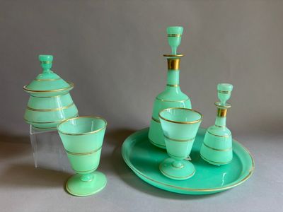 un service en verre vert orné d'une bordure dorée, posé sur une assiette
