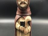 figurine en bois représentant un moine tenant un téléphone portable