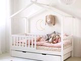un lit de bébé blanc avec une parure de lit et des oreillers roses