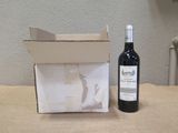 une bouteille de vin posée sur une table à côté d'une boîte