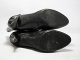 une paire de chaussures en cuir noir posées sur une surface blanche, sur fond blanc