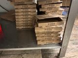 pizza boxes stacked on top of a metal cart in a kitchen