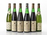six bouteilles de vin sont alignées sur une surface blanche
