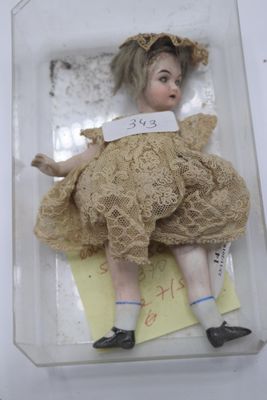 une petite poupée dans une boîte sur laquelle est accrochée une étiquette